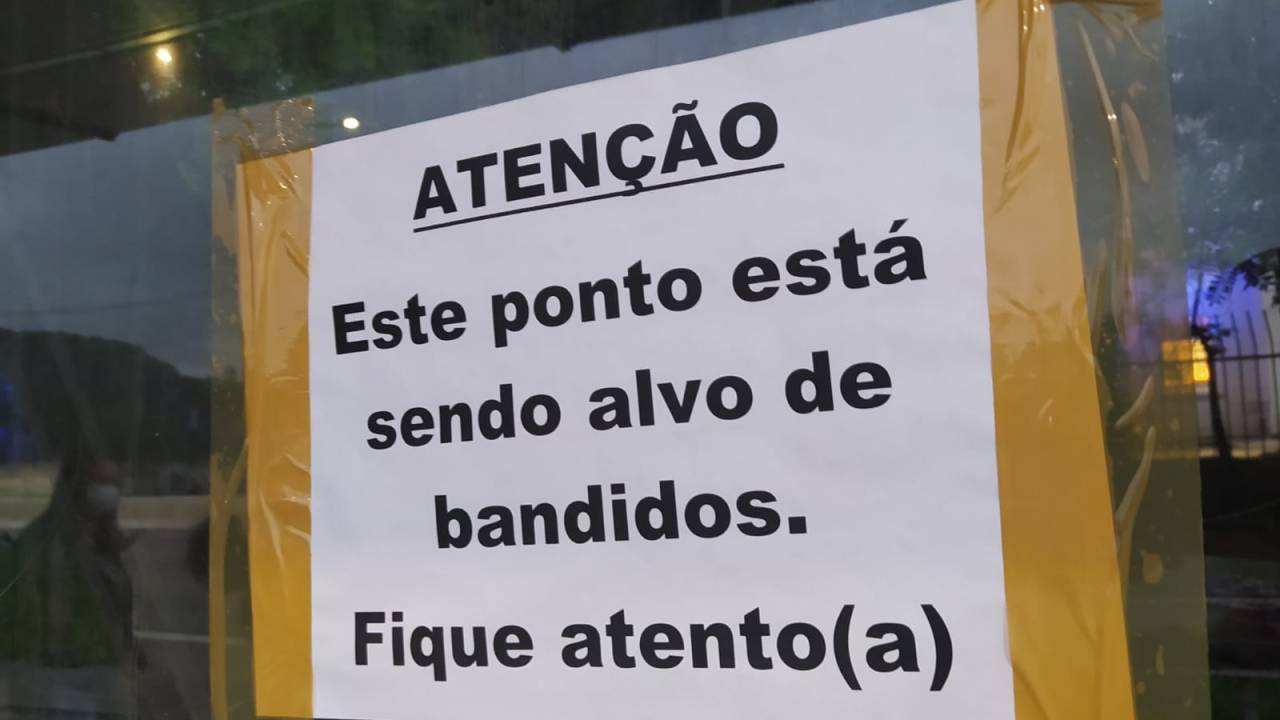 Cartaz em ponto de ônibus avisa que local é alvo de bandidos