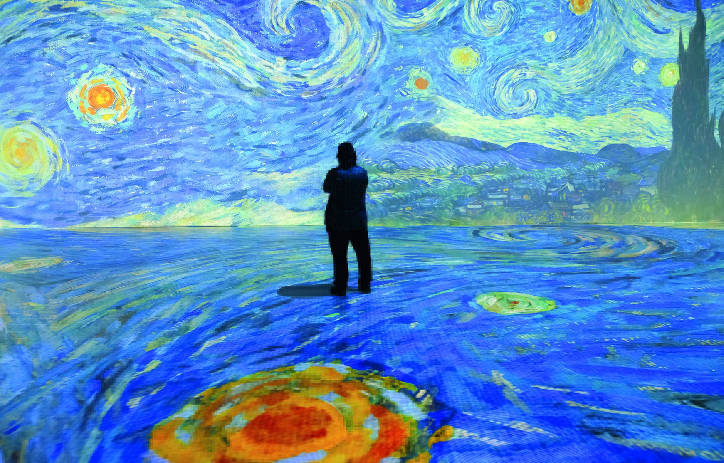 Imagem mostra salão com pintura projetada no chão e na parede. Uma pessoa em pé está no centro da imagem, de costas.