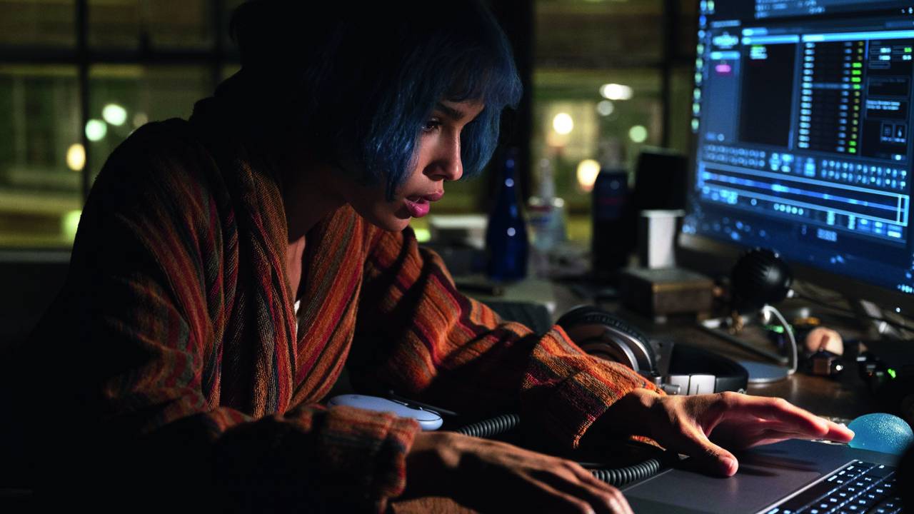 Imagem mostra mulher de cabelo azul em frente a computador.
