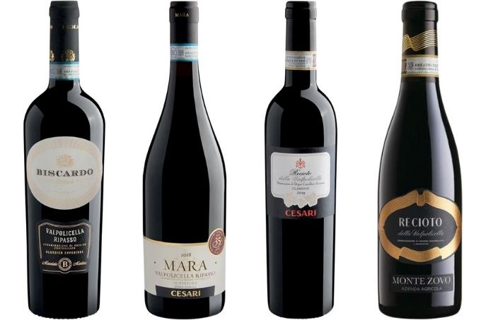 Quatro garrafas de vinho de diferentes rótulos e formatos dispostas sobre fundo branco