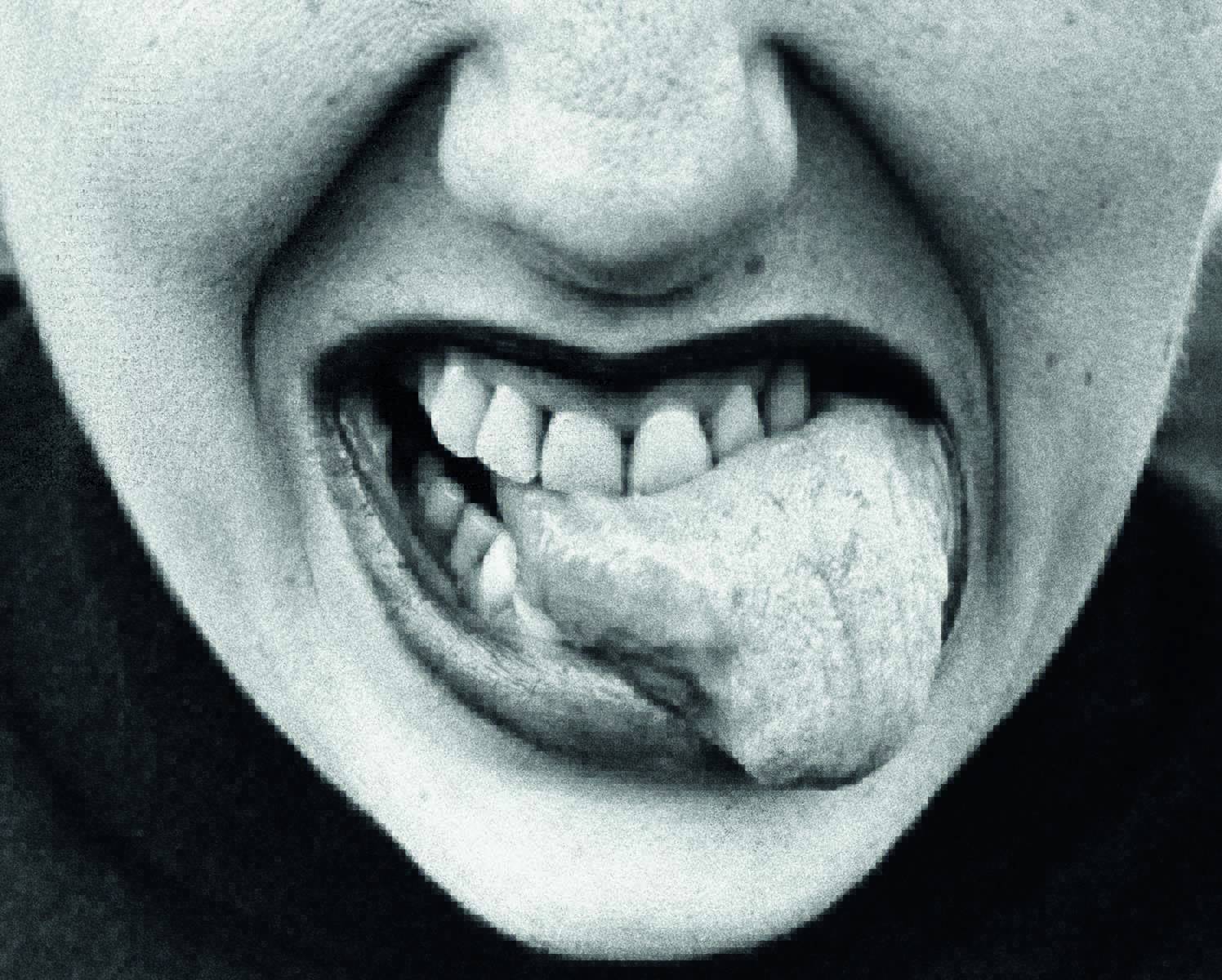 Imagem mostra boca de mulher com os dentes mordendo a própria língua.