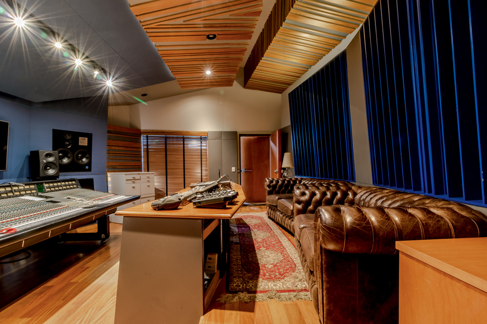 Imagem mostra estúdio com sofá de couro e mesa de som