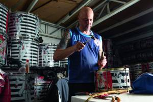 Eduardo Rocha realizando manutenção de instrumentos de percussão no barracão da Mocidade Unida da Mooca