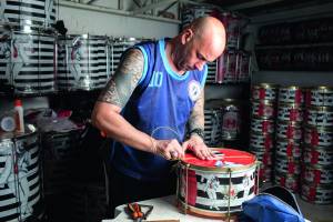 Eduardo Rocha realizando manutenção de instrumentos de percussão no barracão da Mocidade Unida da Mooca.