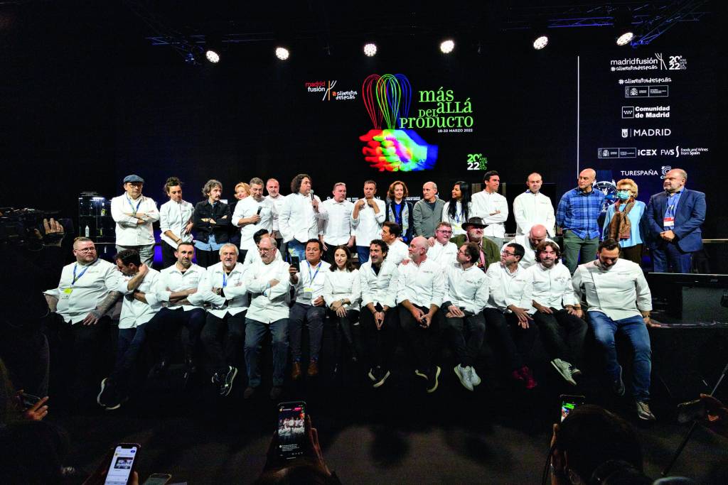 Imagem de homens e mulheres (a maioria vestindo uma roupa de chef de cozinha branca) enfileirados