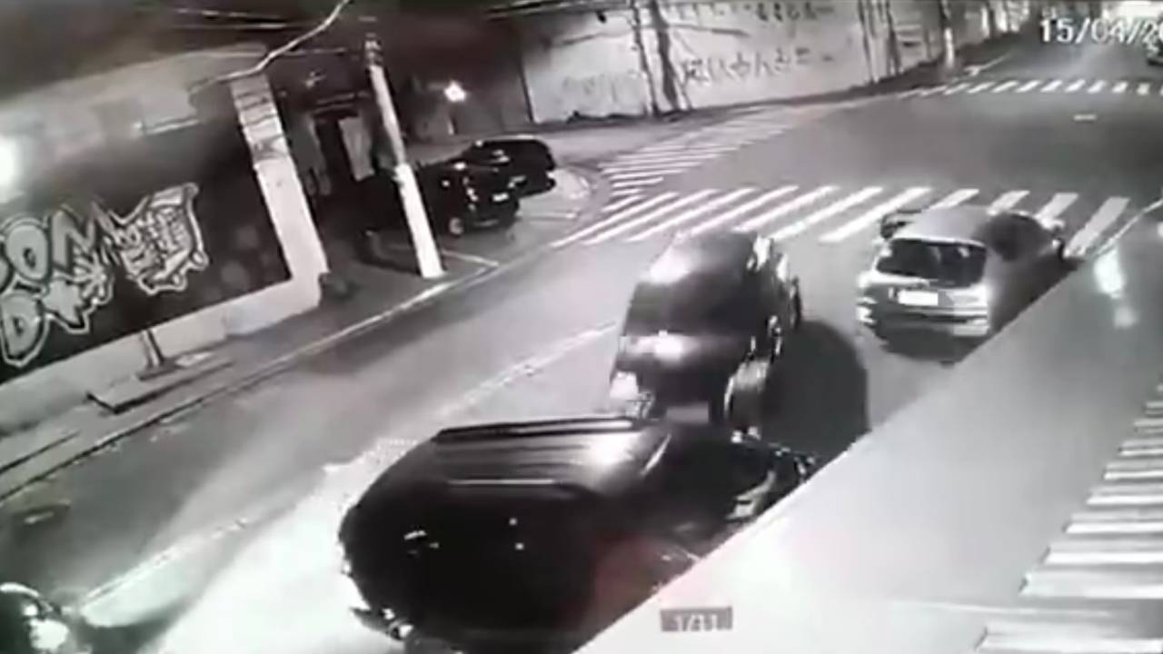 Imagem mostra um carro em velocidade em direção a outro carro, que entra em uma garagem