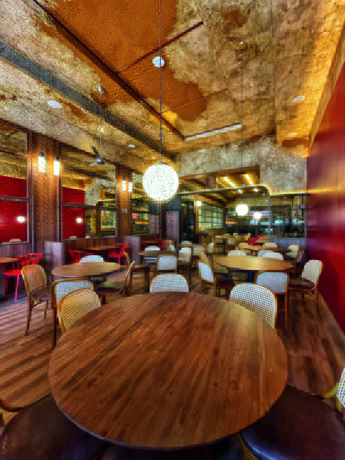Interior do restaurante francês Merci, no Vila Anália. Com paredes de madeira lustres aredondados e minimalistas, o local tem mesas redondas e cadeiras de madeira