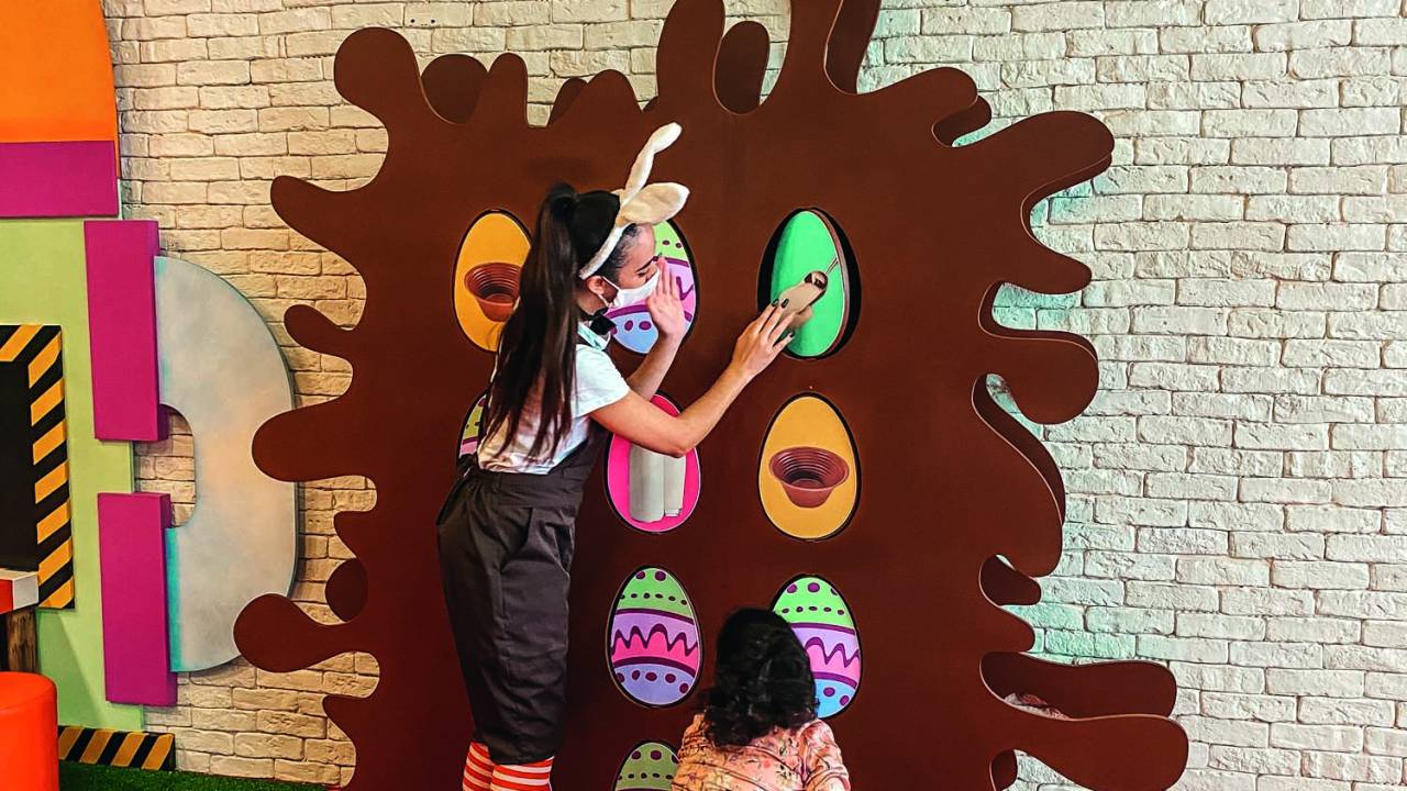 Uma monitora vestida de coelho e uma menina brincam em um jogo da memória 3D com temática de ovos de Páscoa