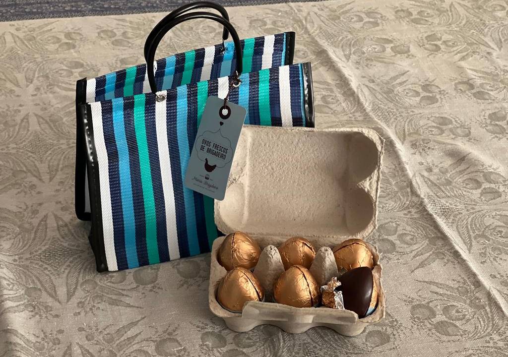 Imagem de um caixa de com ovos de chocolate ao lado de uma sacola