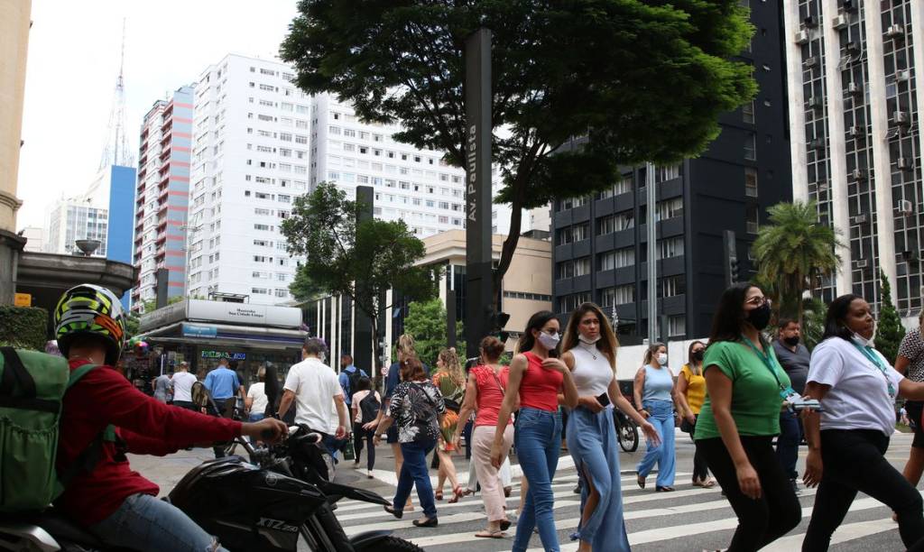 Pessoas caminham pela Avenida Paulista, algumas já sem máscara
