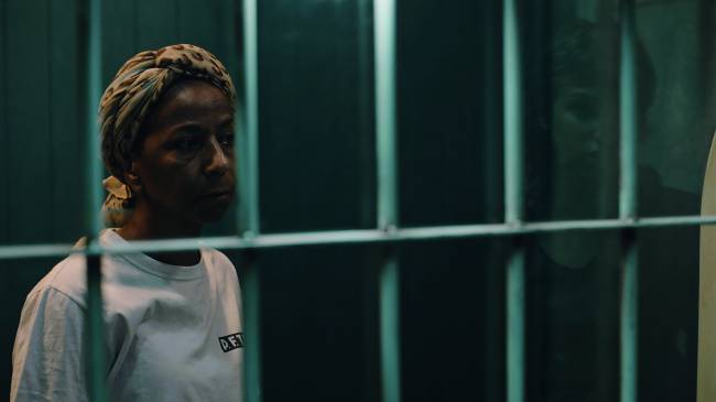 sentença – credito amazon prime video 2.jpg Imagem mostra rosto de mulher séria atrás de grades azuis.