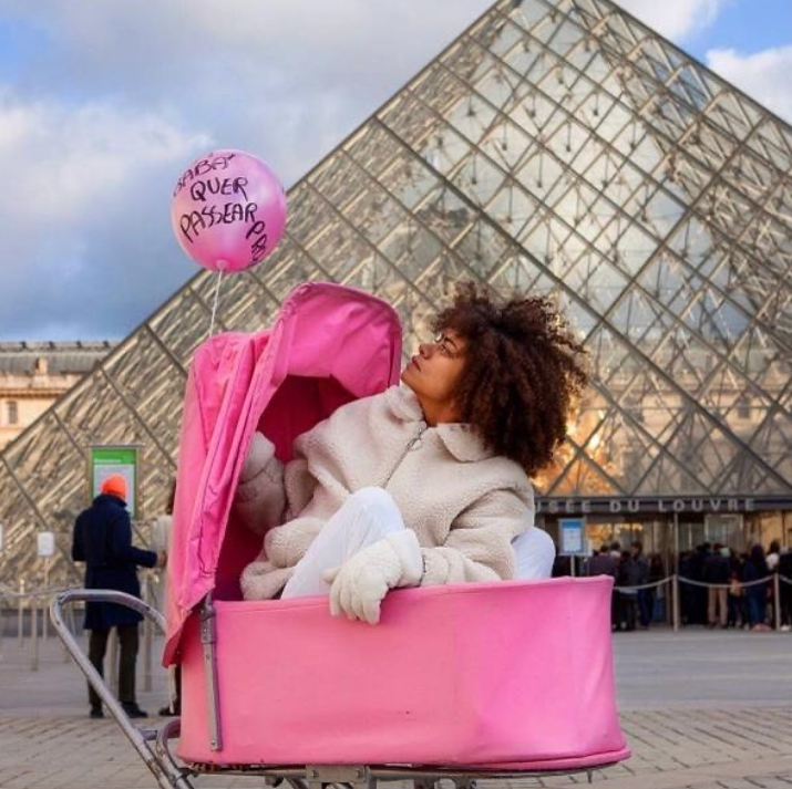 Ana Flávia posa em carrinho de bebê rosa em frente à pirâmide do Louvre.