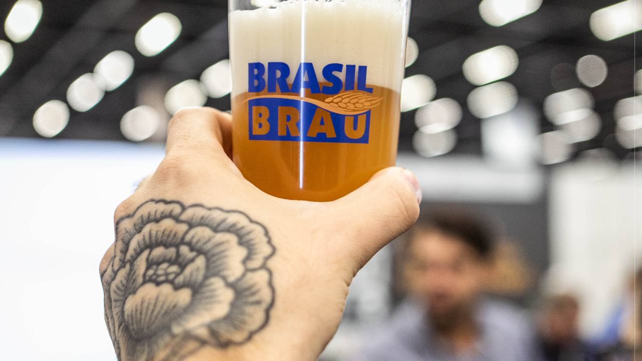 Mão com tatuagem segura copo de cerveja