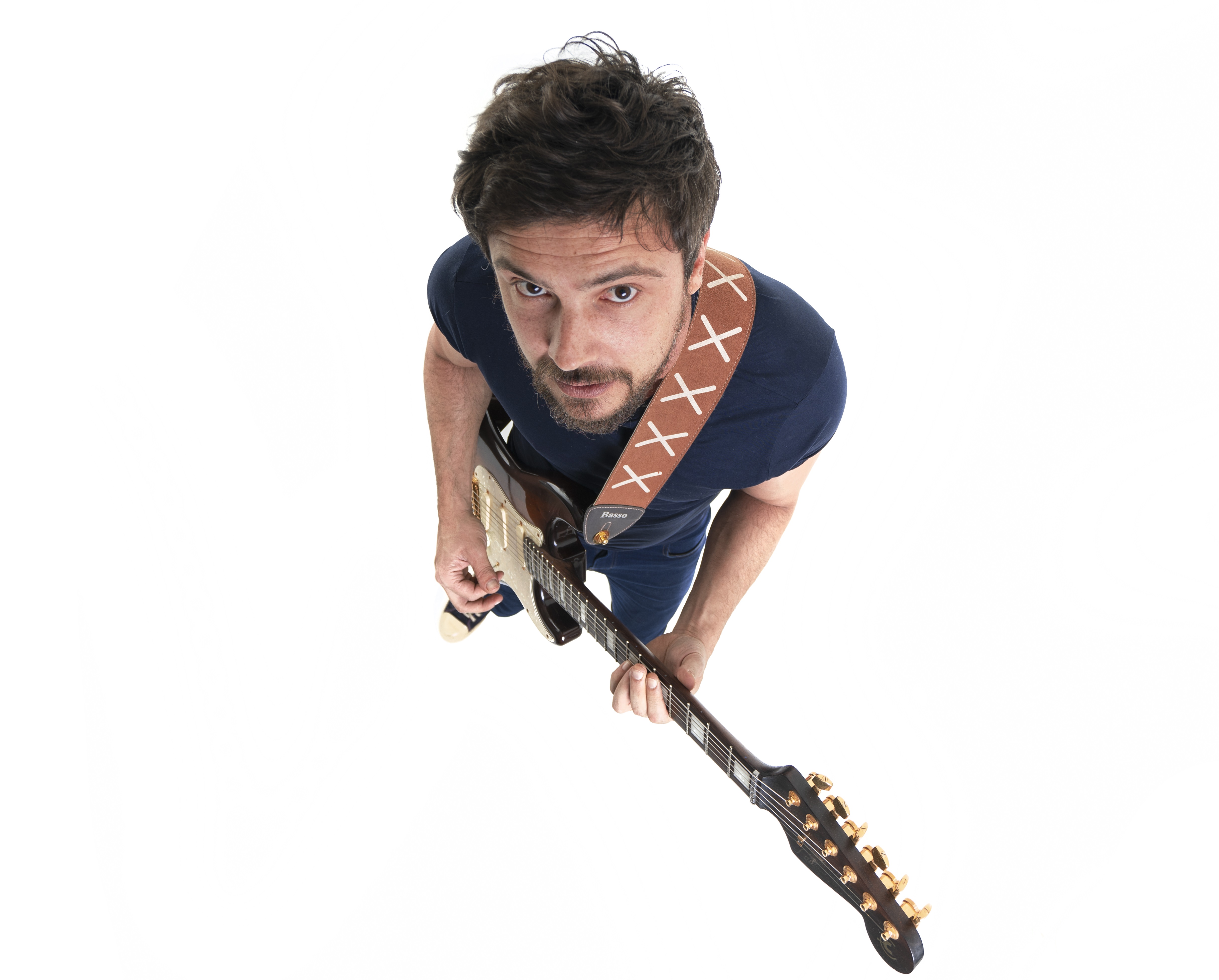 Foto do alto, com Sérgio Guizé visto de cima segurando uma guitarra.