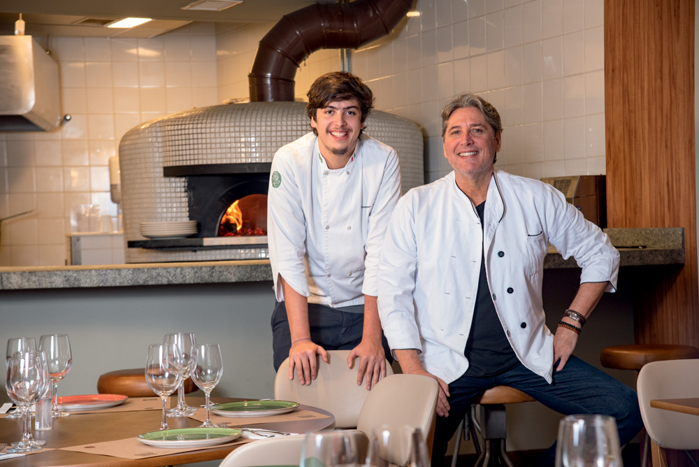 Franco Ravioli e Lorenzo Ravioli posam juntos no ambiente da pizzaria