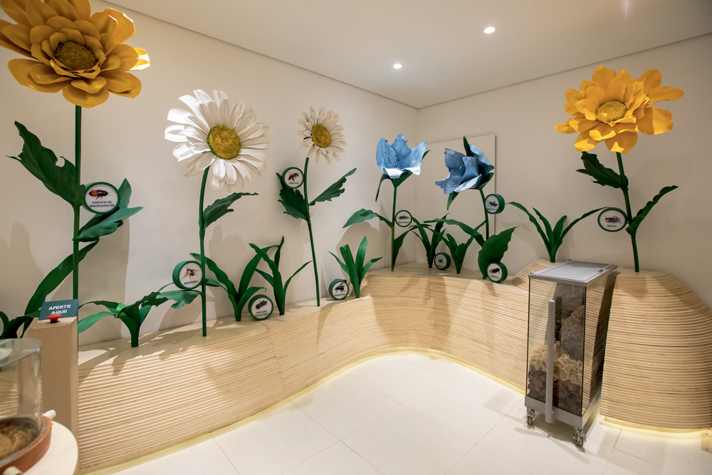 Sala com flores artificiais gigantes em bancadas de madeira