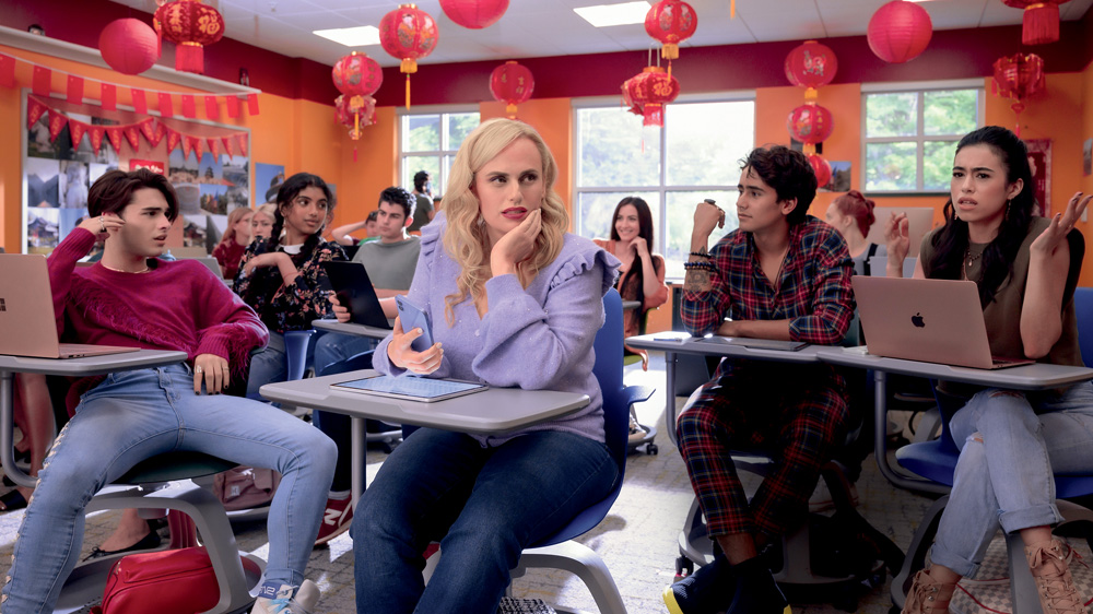 Imagem mostra sala de aula com decoração chinesa e diversas pessoas jovens sentadas em carteiras.