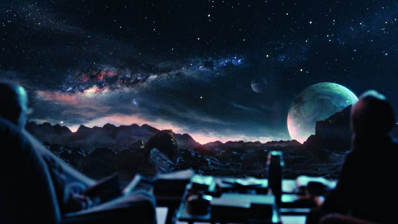 Imagem mostra paisagem espacial, com céu repleto de estrelas e planetas.