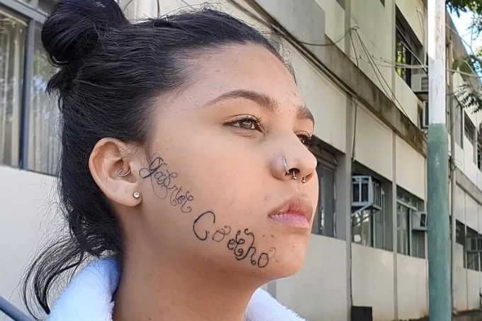 Tayane Caldas aparece com o lado do rosto direito virado, mostrando a tatuagem que seu ex-namorado fez à força em seu rosto
