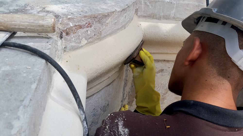 Trabalhador de capacete lixa afrescos brancos do Casarão