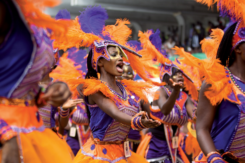 Imagem mostra mulher com figurino carnavalesco dançando.