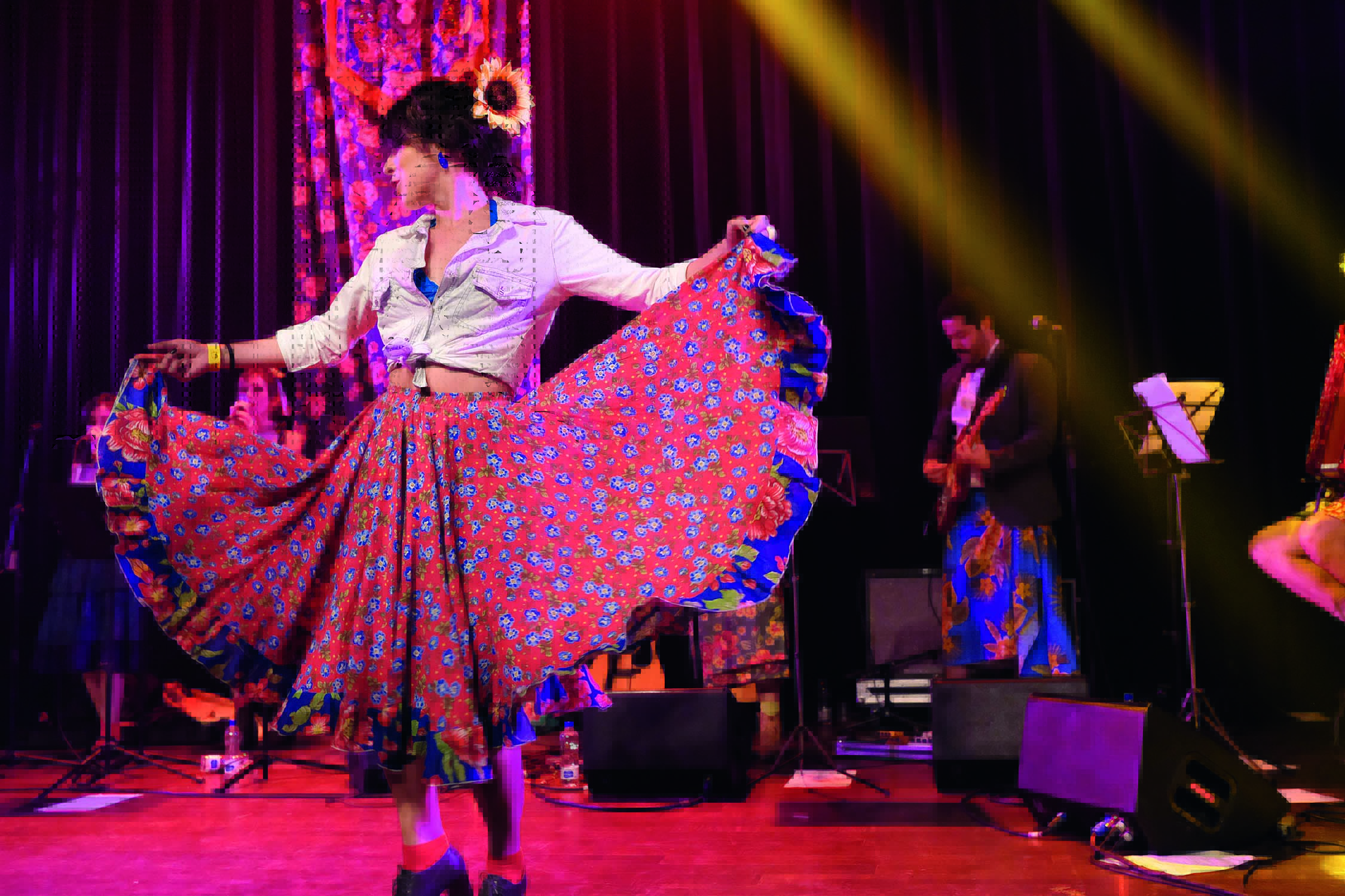 Imagem mostra mulher de saia colorida dançando em palco.