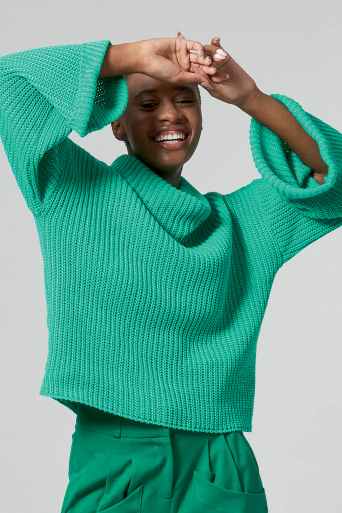 Modelo negra e magra usa blusão de tricô verde com gola alta
