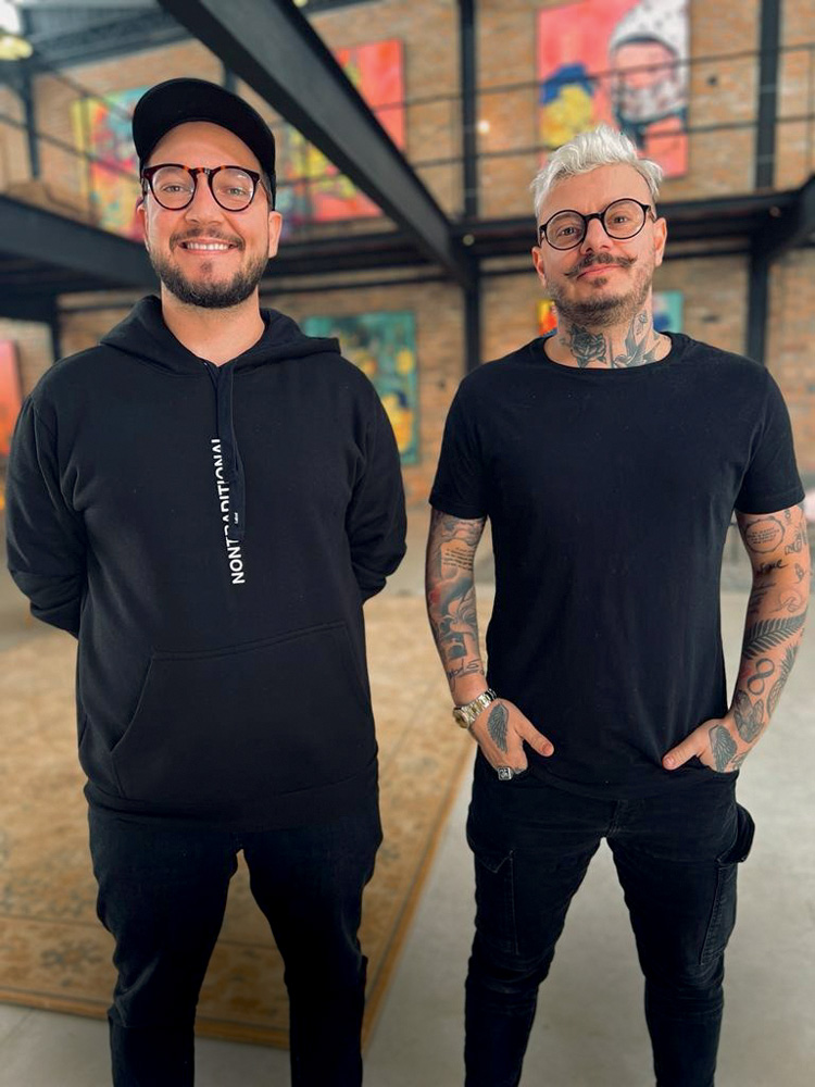 Bruno Garms e Bruno Bernardo – LabOF (Vitor Faria-Divulgação).jpeg Garms e Bernardo posam de pé, lado a lado. Ambos usam óculos de grau e roupas pretas.