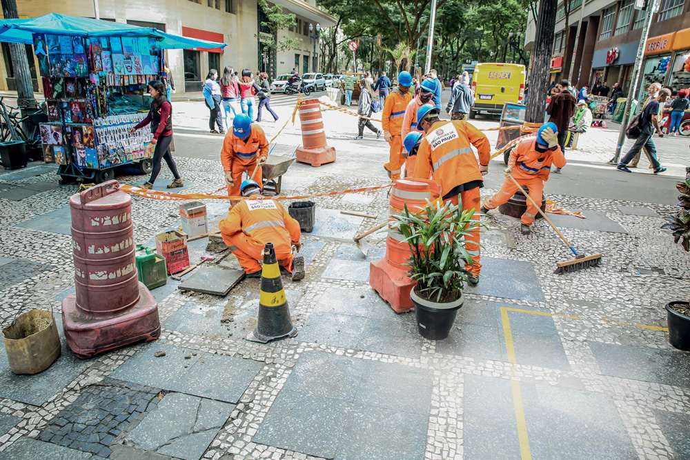 Imagem mostra funcionários da prefeitura arrumando calçada.