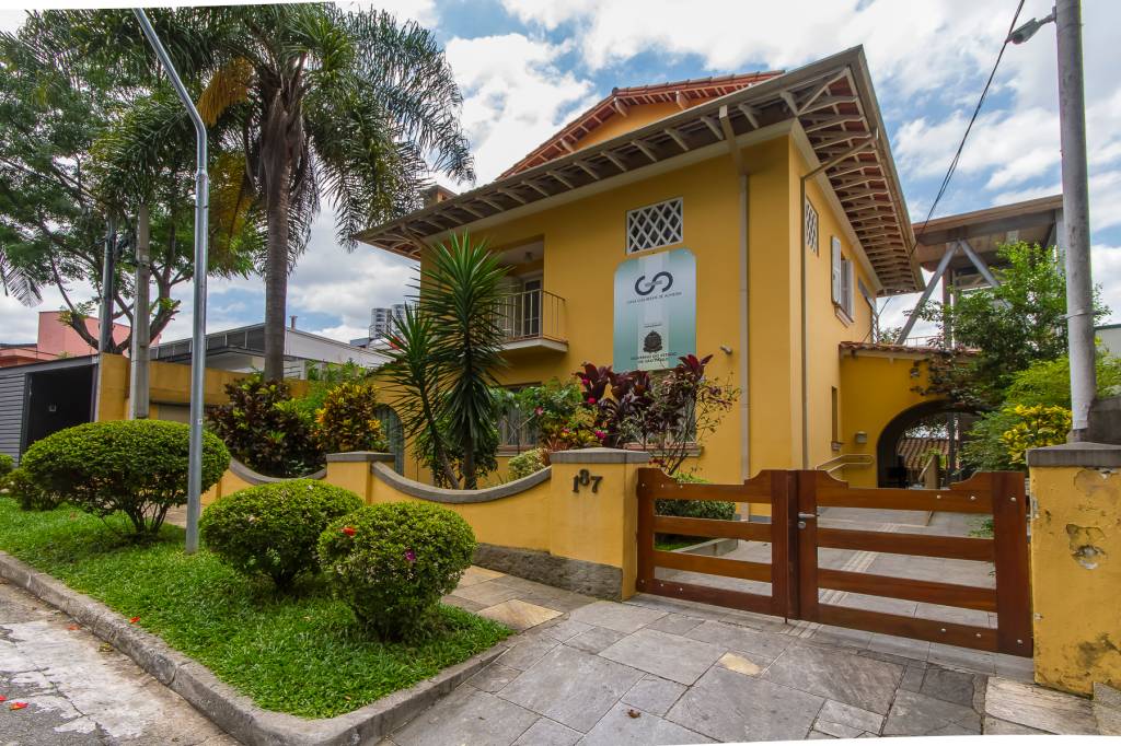 Casa Guilherme de Almeida, uma casa antiga amarela, que tem um jardim na calçada