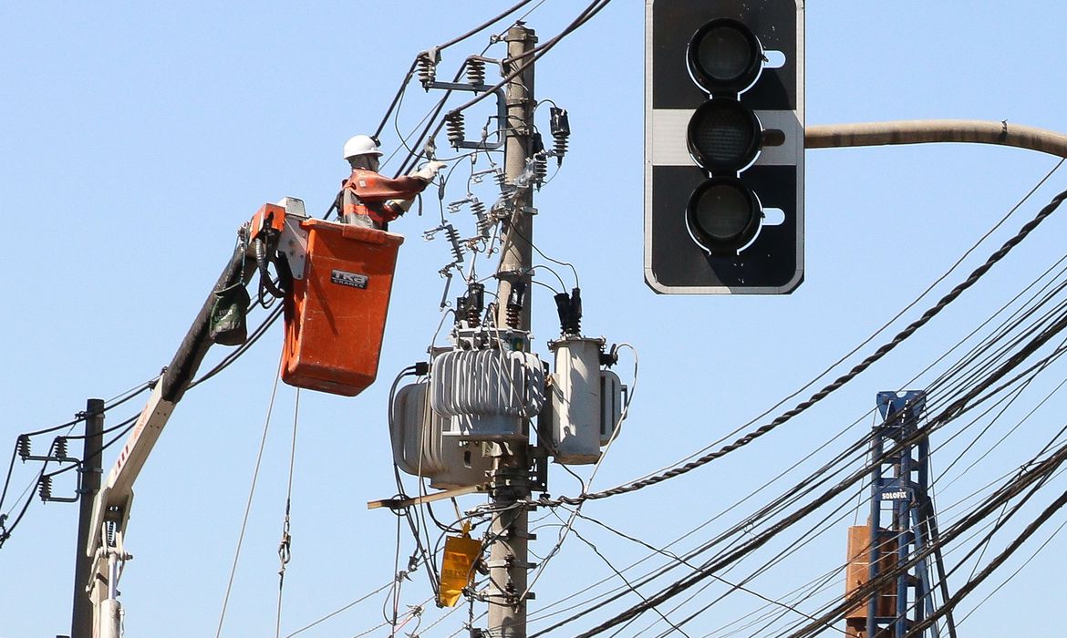 uncionários da Enel fazem manutenção em poste de energia elétrica no bairro de Pinheiros.