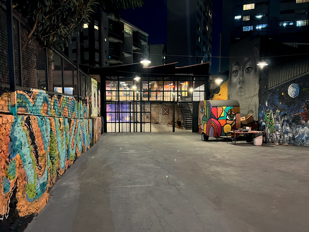 LabOF (Vitor Faria-Divulgação) (5).jpg Foto exibe galpão de chão cinza, food truck no fundo e janelões de vidro, com grafite colorido na parede à esquerda.