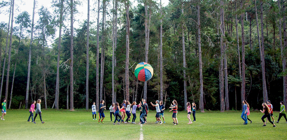 Crianças brincam com bola gigante em campo aberto