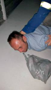 Manoel Sabino imagem mostra homem com o rosto no chão e uma sacola ao lado
