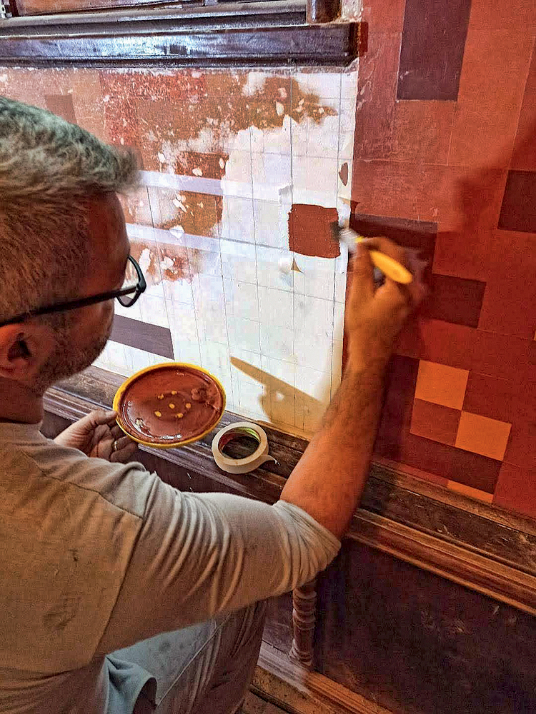 Trabalhador pintando parede com tinta marrom