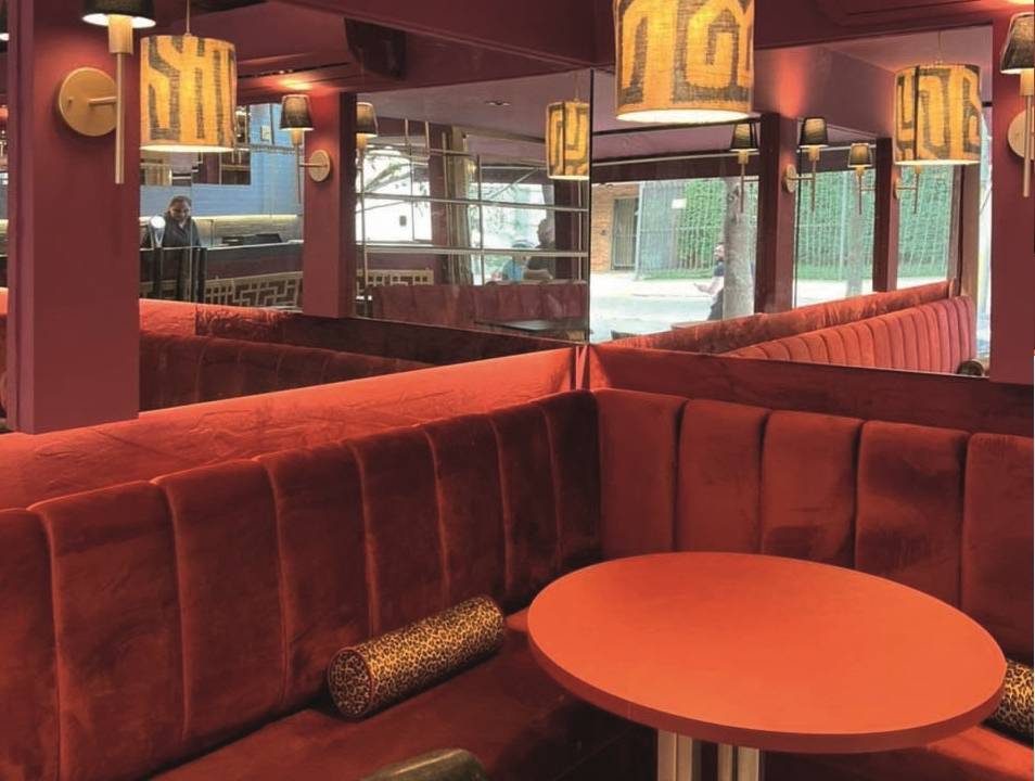 Ambiente de bar com bancos estofados em tecido aveludado e paredes vermelhas