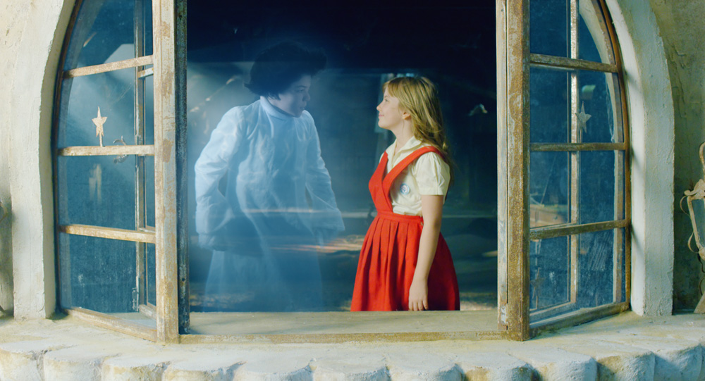 Imagem mostra menina com vestido vermelho em frente a fantasma