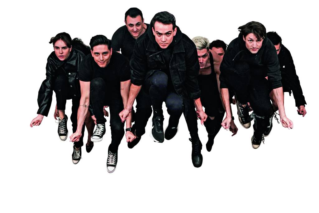 Imagem mostra elenco de pessoas pulando ao mesmo tempo, com os braços abaixados.