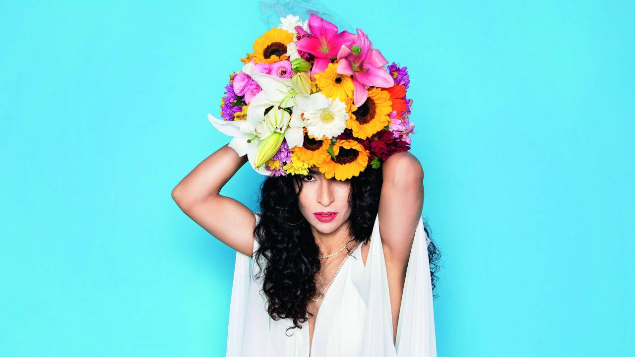 Marisa Monte posa segurando um buquê de flores na altura da cabeça
