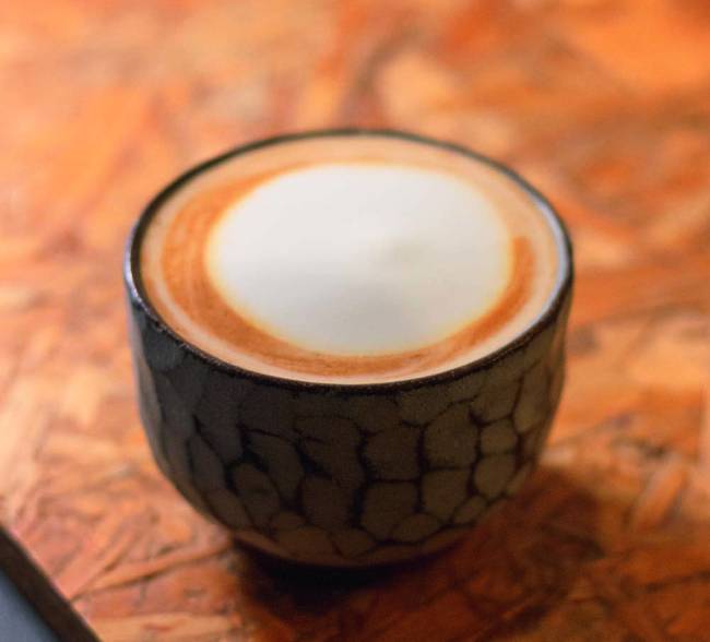 Xícara baixa de cerâmica com café servido com leite e espuma