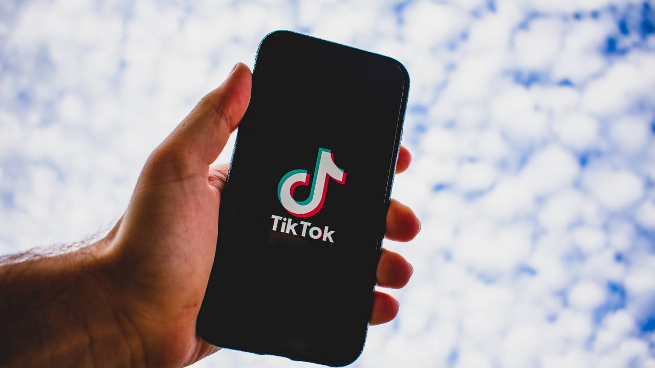 Foto mostra uma mão segurando um celular, cuja tela mostra o logo do TikTok.