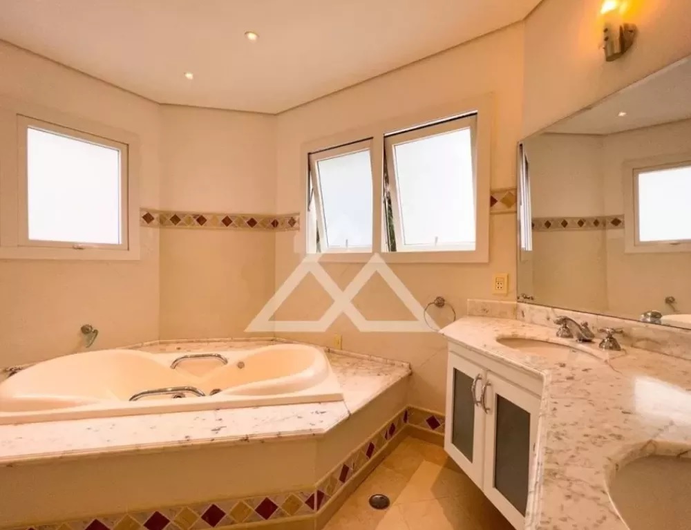 Foto exibe banheiro com banheira, três janelas e pia.