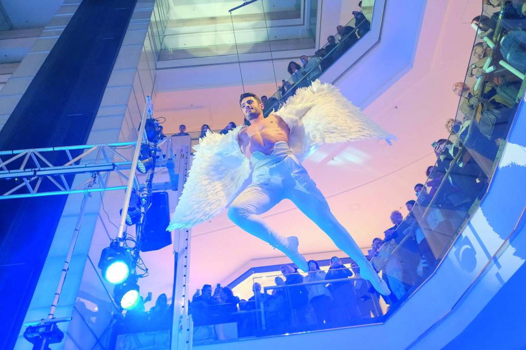 Imagem mostra homem vestido de anjo suspenso em vão de shopping.