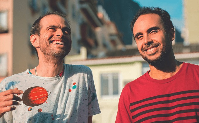 Imagem mostra dois homens sorrindo em dia ensolarado