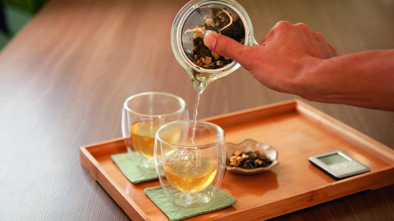 chá sendo despejado em uma xícara transparente