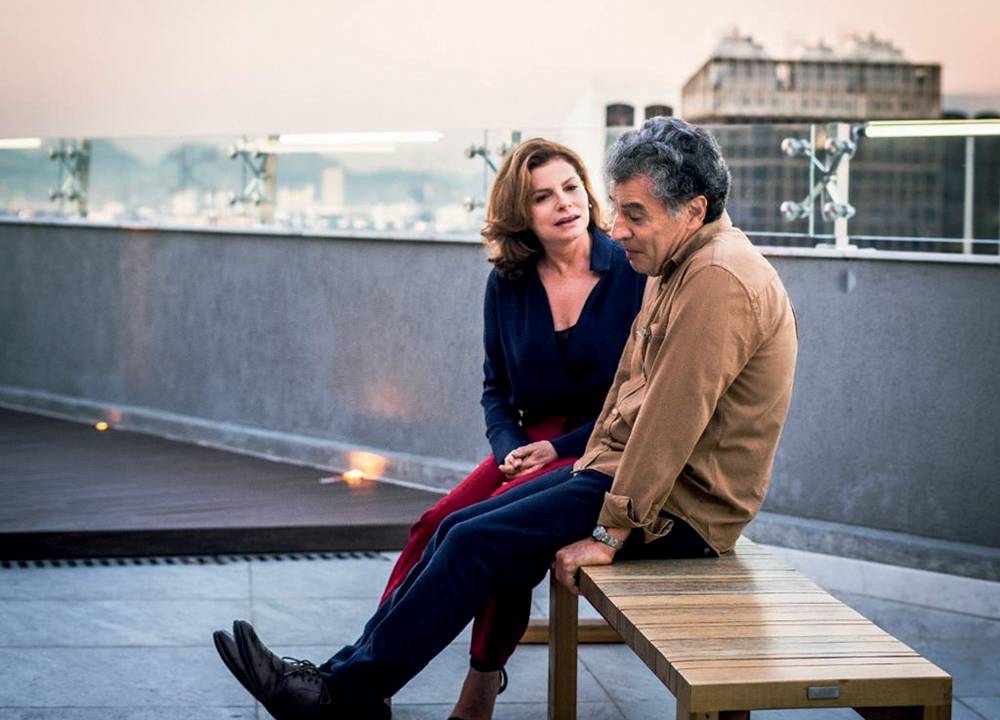 Imagem mostra homem e mulher em terraço de prédio conversando