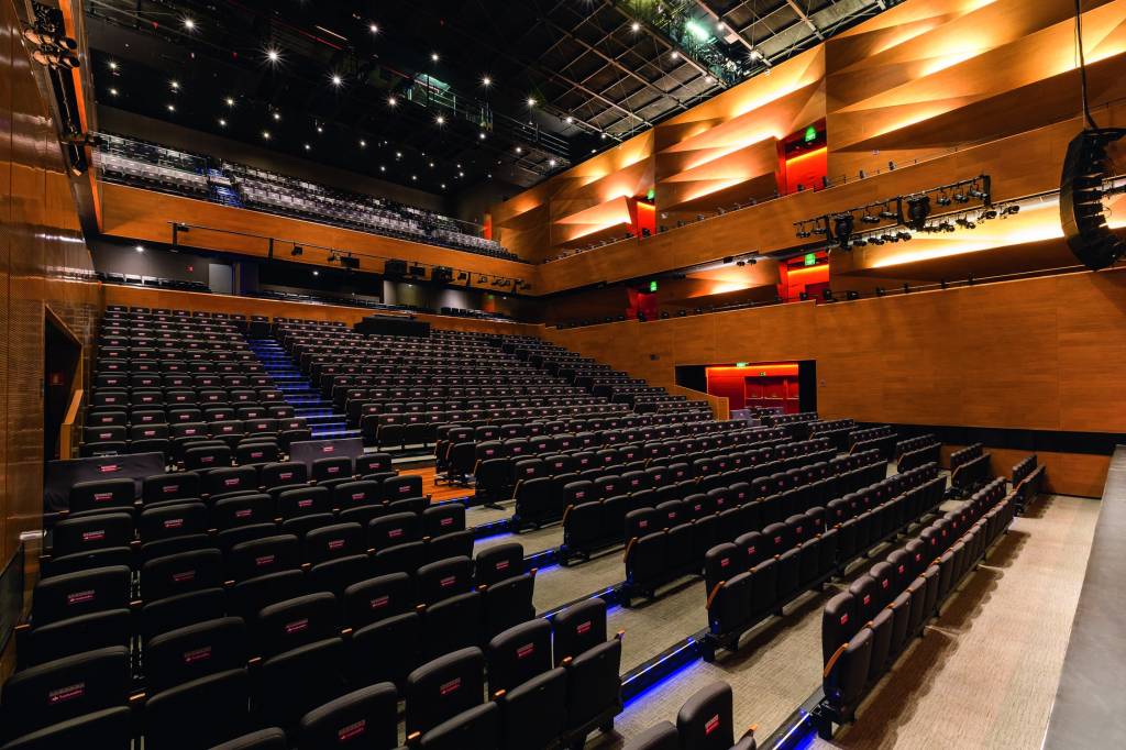 Teatro Santander Imagem mostra plateia de teatro com paredes de madeira e poltronas pretas