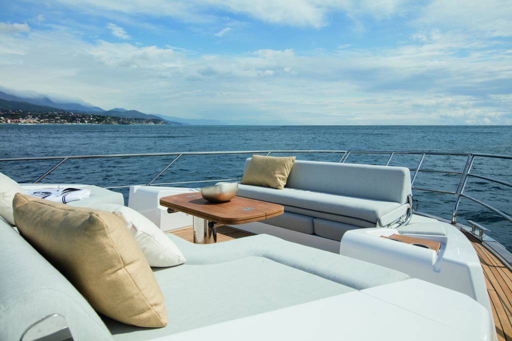 Azimut 62 (Divulgação Azimut Yachts) (11) Foto de varanda com sofás brancos e mesinha de madeira em iate.
