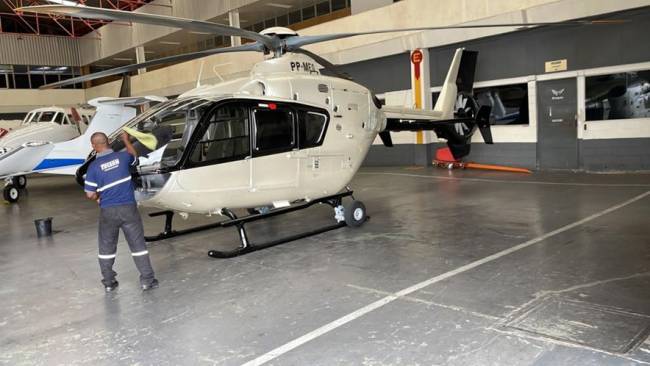 Foto mostra hangar com helicóptero.