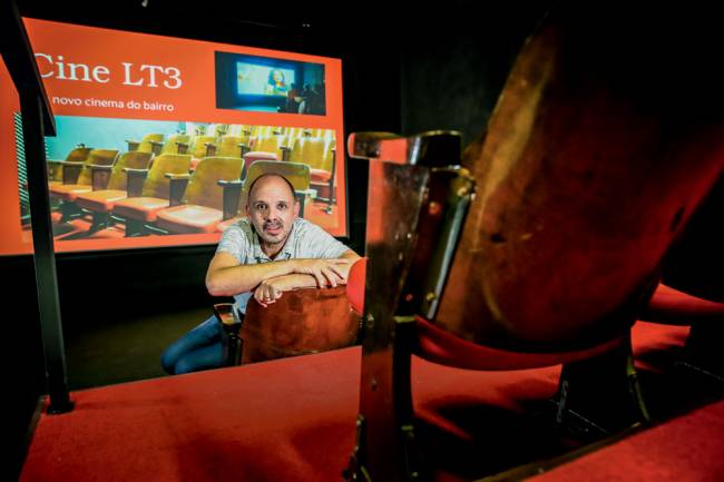 Carlos Costa com o interior do cinema de rua que fundou atrás dele